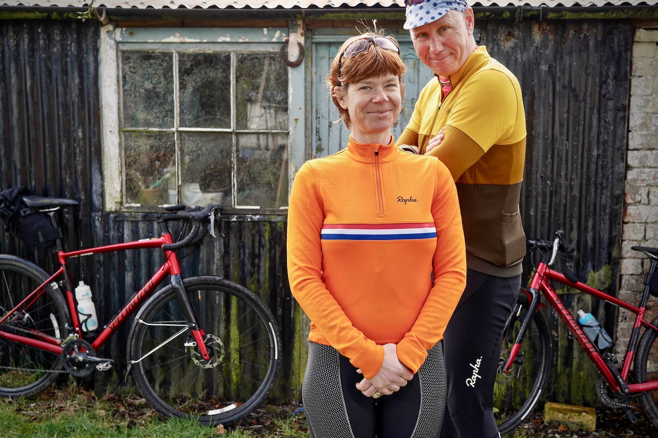 two cyclists standing smiling at camera with bikes along cycle routes